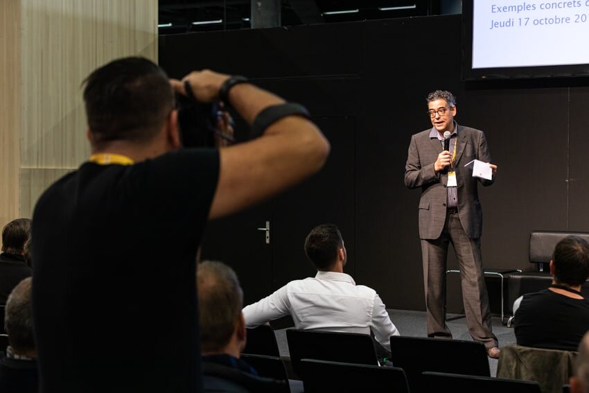 Un journaliste prend une photo d'un orateur sur la scène de la foire du bois.
